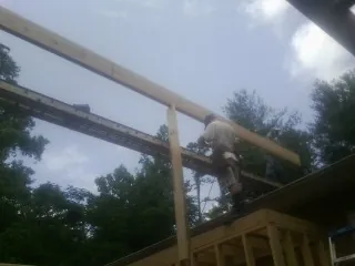 Carpenter setting a ridge beam over a new addition frame — Ice Dam Removal by Roofing Brothers in Bristow