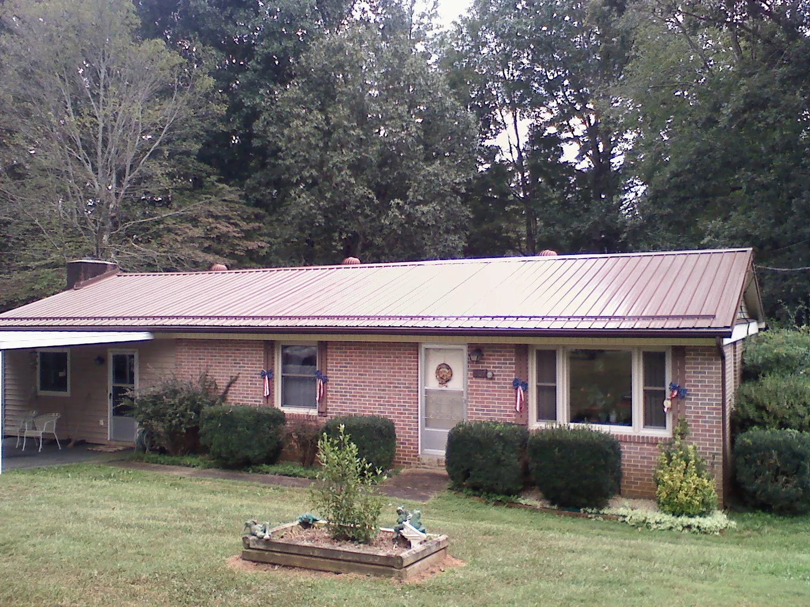 Bronze metal roof on a brick ranch home with a carport in Bristow