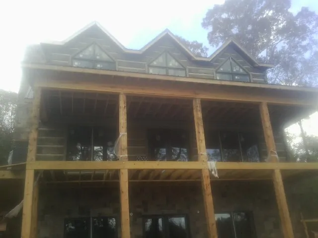 Dormers and porch framing on a large log home under construction — Roof Coating work by our crew in Bristow
