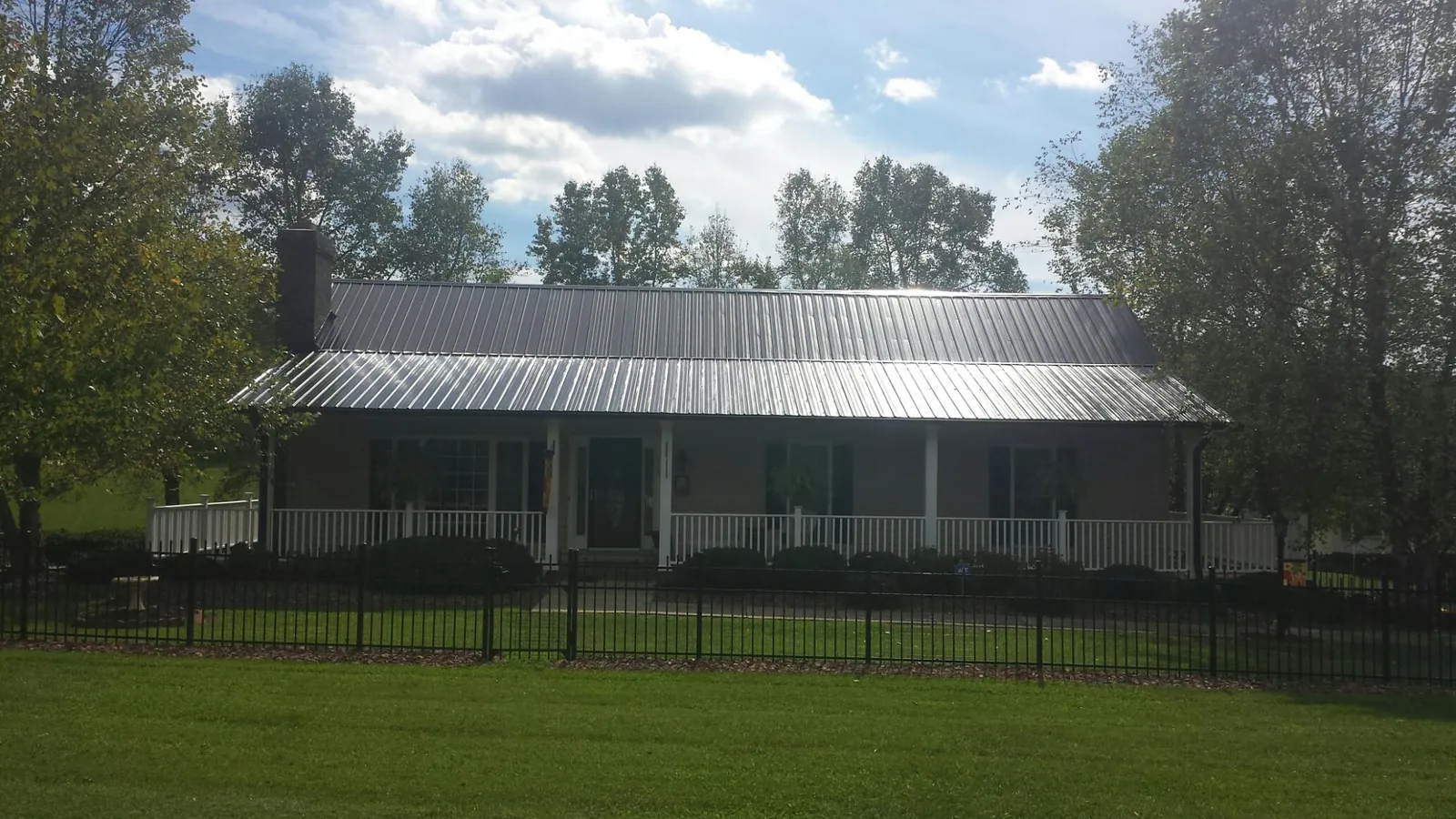 Gray metal roof on a brick ranch with a full width front porch — Gutter Guard Installation work by our crew in Bristow