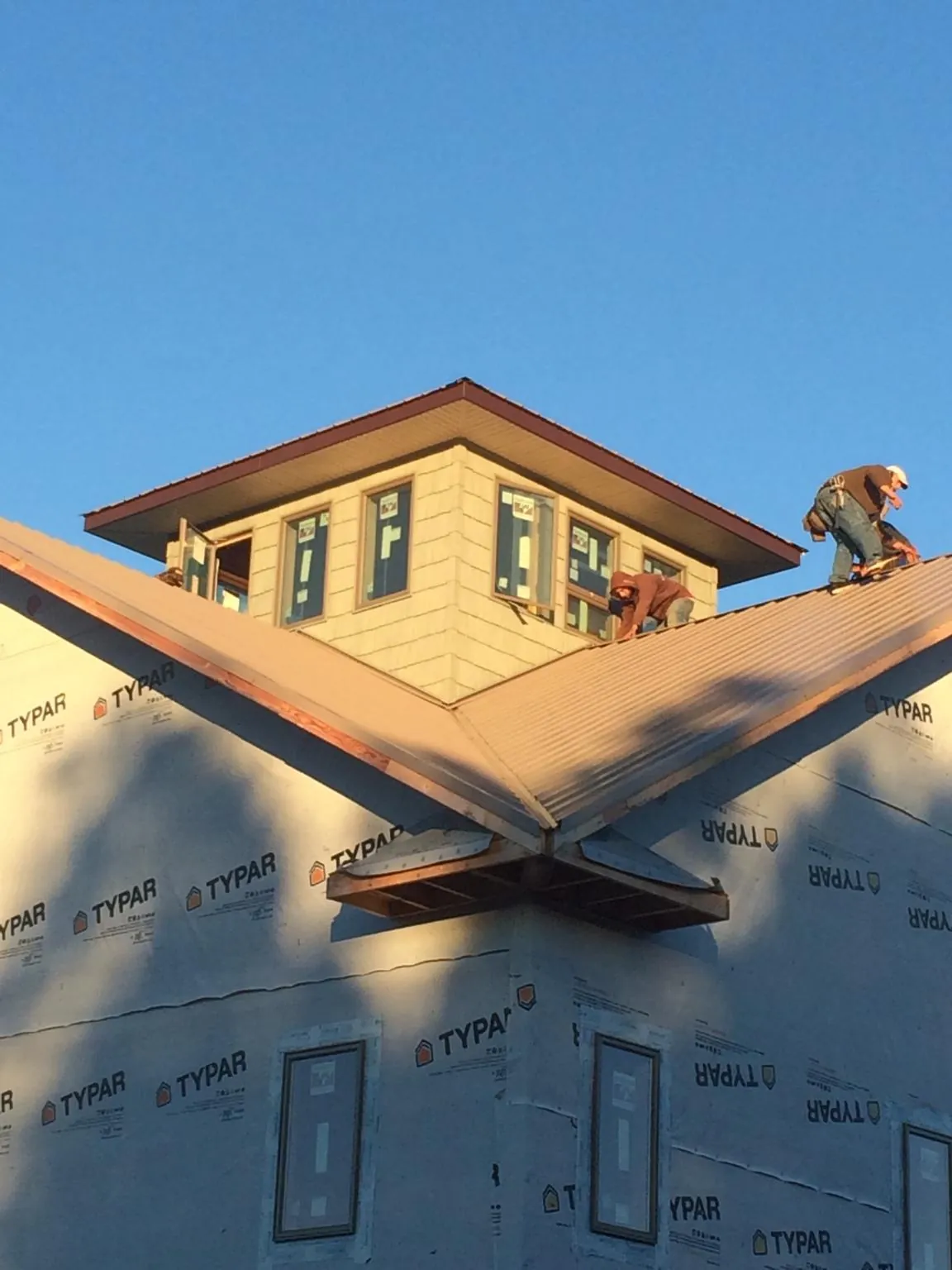 Roofers working around a rooftop cupola on a new metal roof at sunset — Roof Waterproofing in Bristow by Roofing Brothers